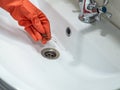 Hand in orange gloves holds many hair loss on filter in washbasin while cleaning Royalty Free Stock Photo