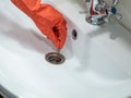 Hand in orange gloves holds many hair loss on filter in washbasin while cleaning Royalty Free Stock Photo