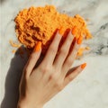Hand with orange nails on marble with vibrant orange powder Royalty Free Stock Photo