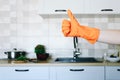 Hand in orange protective glove showing thumb up on kitchen background Royalty Free Stock Photo