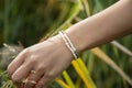 Hand outdoor touching plants with pearl and hematite bracelet