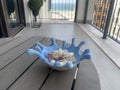 A hand painted blue and white bowl filled with sea shells on a terrace table overlooking the sea