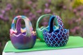 Hand-painted Easter egg baskets on a green pedastal in front of purple lavender flowers