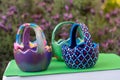 Hand-painted Easter egg baskets on a green pedastal in front of purple lavender flowers