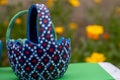 Hand-painted Easter egg baskets on a green pedastal in front of yellow and orange spring flowers