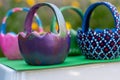 Hand-painted Easter egg baskets on a green pedastal in front of yellow and orange spring flowers