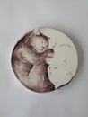 The hand-painted glass water saucer features a charming design of two cats, one white and one brown