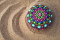 Hand painted mandala rock on sand