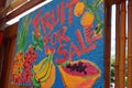A hand painted sign attracts customers to a fruit vendor