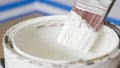 Hand of painter dipping a brush into a bucket with white paint. Renovation Royalty Free Stock Photo