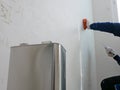 A hand of a painter holding on a piece of cloth, soaked with thinner, removing sticky rough glue and tape remain on the old Royalty Free Stock Photo