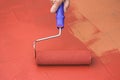 Hand painting a red floor with a paint roller Royalty Free Stock Photo