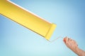 Hand painting yellow stripe with paint roller on blue background