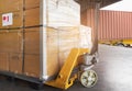 Hand pallet jack with stacked of package boxes on pallet rack waiting to load into shipping container. Cargo shipment boxes. Royalty Free Stock Photo