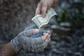 The hand of a passer-by gives a dollar to the hands of a homeless man in gloves. Poverty, hunger, unemployment