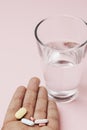 Hand of patient with pills and a glass of water Royalty Free Stock Photo