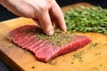 hand patting dry herb rub on beef steak