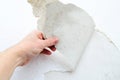 Hand peeling away old, textured wallpaper from a white wall Royalty Free Stock Photo