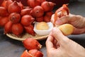 Hand Peeling Salak Fruit with Blurry Fruit Clusters in the Backdrop