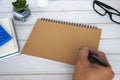 Hand with pen on blank brown notepad with space customizable for text or ideas. Copy space for ideas Royalty Free Stock Photo