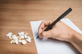 Hand with pen over blank paper form with pills Royalty Free Stock Photo