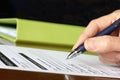 Hand with Pen Signing Form by Green Folder Royalty Free Stock Photo