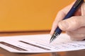 Hand with Pen Signing Form on Orange Background