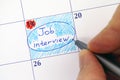 Hand with pen writing reminder Job Interview in calendar