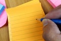Hand pencil writes in a blank orange notepad