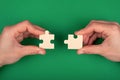 Hand of people connecting puzzles on a green background of business solutions and represent team support