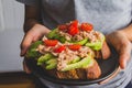 Hand people holding a delicious sandwich with tuna fish and sliced avocado on top tomato Royalty Free Stock Photo