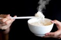 Hand of people using white chopsticks holding hot jasmine rice with smoke in white bowl Royalty Free Stock Photo