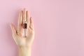 Hand with perfume bottle composition on pink background