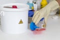 Person cleaning a waste container labeled as biological risk