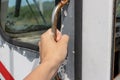 A hand of a person getting into an old rusty commuter bus