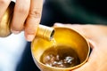 Hand person is pouring water with brass cup. Concept of making merit and dedicating charity in Buddhism Royalty Free Stock Photo
