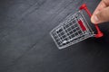 Hand of a person pushing a small shopping cart on a black slate background