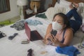 Hand phone addiction in times of covid-19 - young bored and messy Asian girl on chaotic bed as social media addict at coronavirus