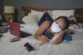 Hand phone addiction in times of covid-19 - young bored and messy Asian girl on chaotic bed as social media addict at coronavirus