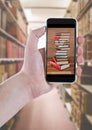 Hand with phone showing book pile against blurry bookshelfs
