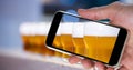 Hand photographing beer glasses through smart phone at bar Royalty Free Stock Photo