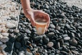 Hand pick up a glass of dirty coffee on black and white rock in garden floor. Background and texture of white and black pebbles st Royalty Free Stock Photo