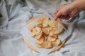 Hand pick up pieces of fresh homemade deep fried crispy  potato chips on a wooden tray, top view. Salty crisps scattered on a tabl Royalty Free Stock Photo