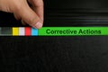 Hand picking corrective action file organizer in black background. Audit findings and root cause analysis