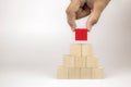 Hand picking a cube shape wooden block toy stacked in pyramid shape without graphics Royalty Free Stock Photo