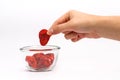 Hand picking dry strawberry from clear glass bowl