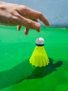 The hand picking Green Plastic Badminton shuttlecock with badminton court background