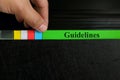 Hand picking guidelines file record in black binder folder. Work guideline concept.