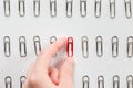 Hand picking among metal paperclips one red, different from others Royalty Free Stock Photo