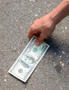 Hand picking money from street floor